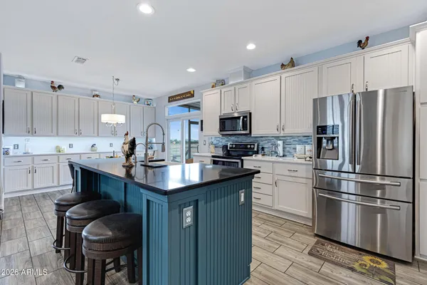 a kitchen with stainless steel appliances a sink a stove a refrigerator cabinets and a center island