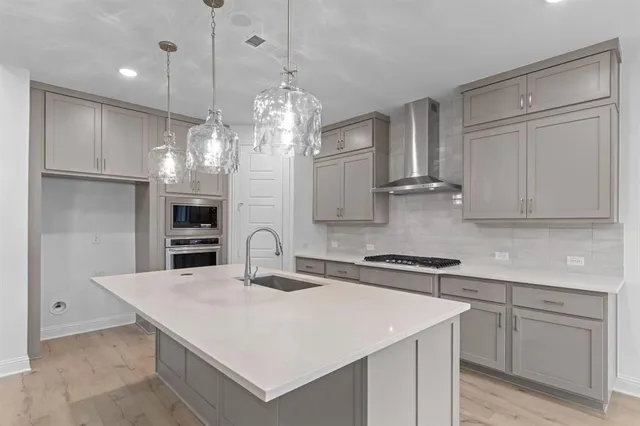 a kitchen with kitchen island granite countertop a sink a counter space appliances and cabinets