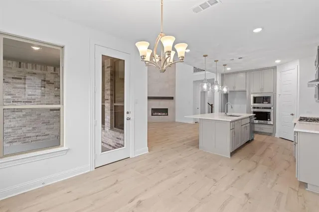 a view of a kitchen with granite countertop a large counter top space stainless steel appliances and a chandelier