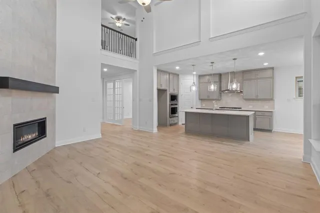a view of kitchen with kitchen island a sink wooden floor and a living room