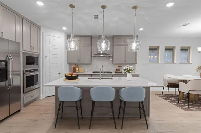 a kitchen with stainless steel appliances a dining table chairs refrigerator and sink
