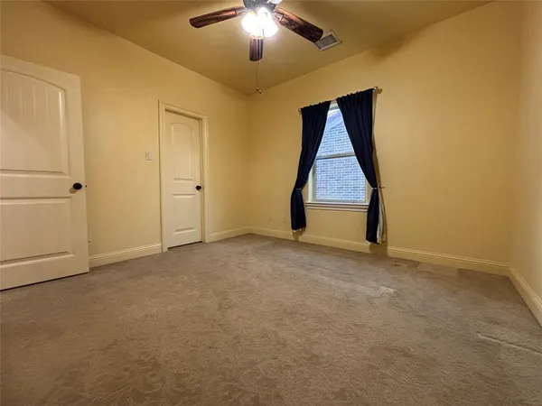 a view of an empty room with a chandelier fan