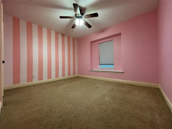 an empty room with a chandelier fan and windows