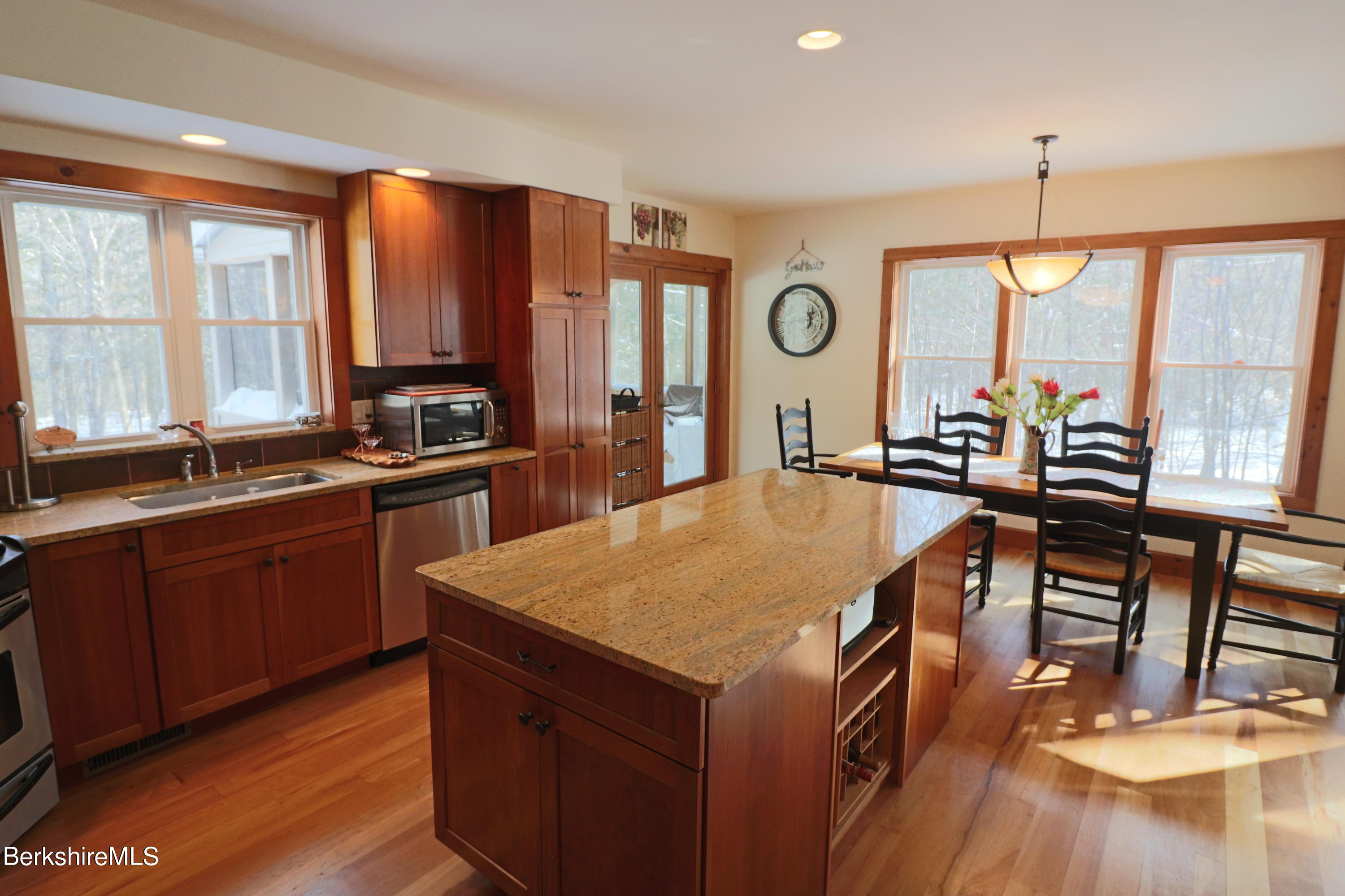453 Ed Jones Road Otis, MA 01253 - Photo 10 of 41 a open kitchen with stainless steel appliances granite countertop a stove a sink dishwasher a dining table and chairs with wooden floor