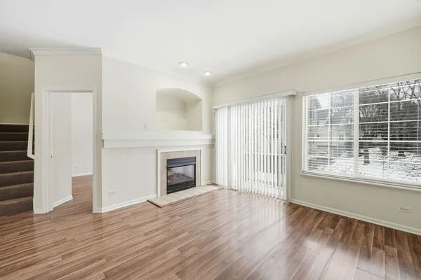 an empty room with wooden floor cabinet and windows