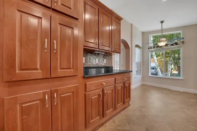 an empty room with chandelier fan and windows