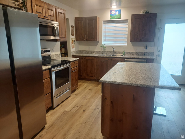 3831 South Powderwood Lane, Unit 111 Mapleton, UT 84664 - Photo 4 of 12 Kitchen featuring wood-finish flooring, stainless steel appliances, a center island with countertop seating, and a window above the double basin sink