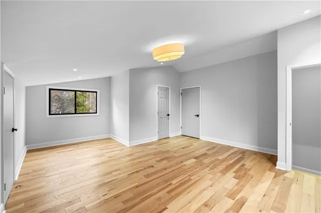 a view of an empty room with window and wooden floor