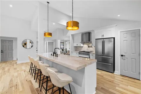 a kitchen with stainless steel appliances granite countertop a table chairs and a refrigerator