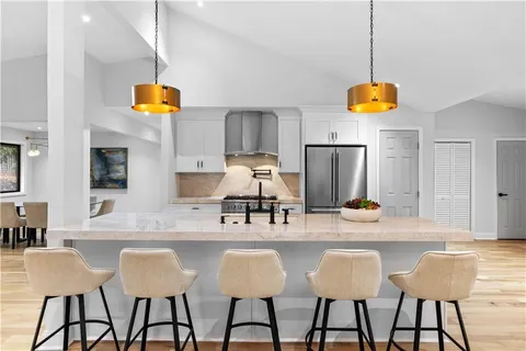 a kitchen with stainless steel appliances kitchen island granite countertop a table and chairs in it