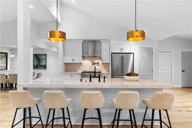 a kitchen with stainless steel appliances kitchen island granite countertop a table and chairs in it