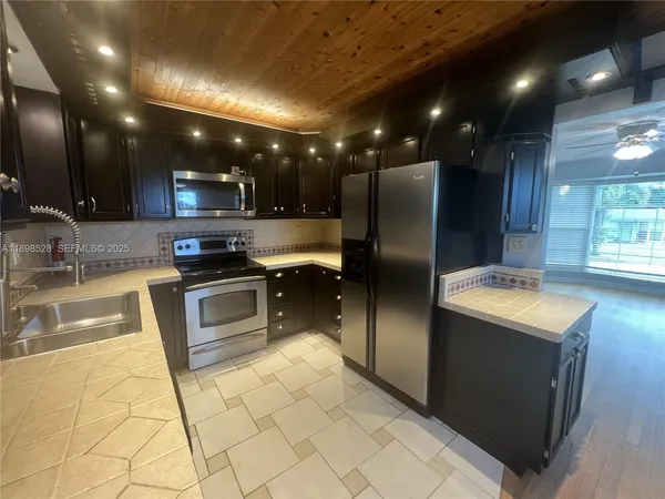 a kitchen with stainless steel appliances granite countertop a sink a stove a refrigerator and a microwave