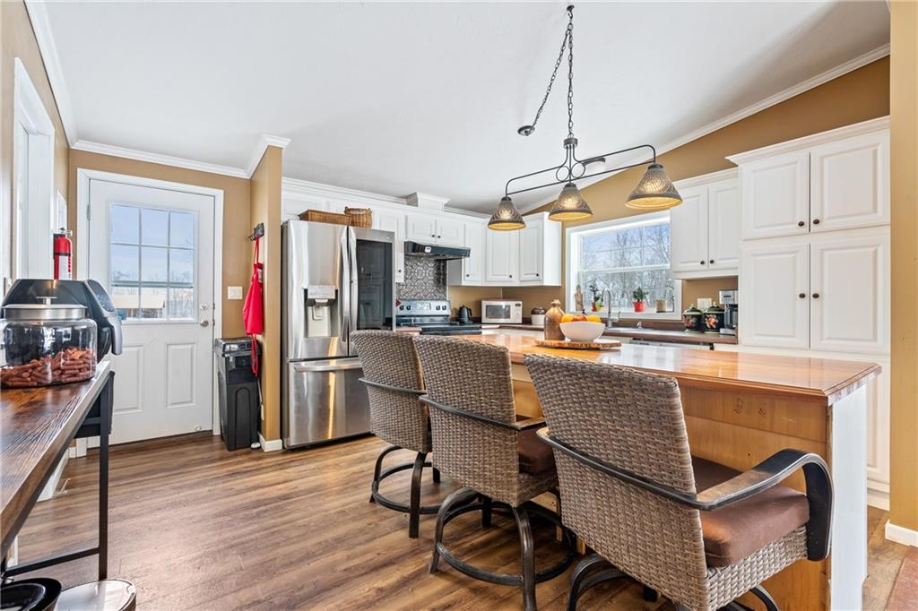 257 Hilltop Acres Road Slippery Rock, PA 16057 - Photo 4 of 25 a kitchen with stainless steel appliances granite countertop a refrigerator a sink dishwasher a dining table and chairs with wooden floor