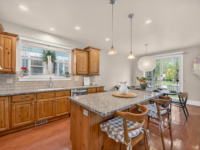 557 Craftsman Way Midway, UT 84049 - Photo 21 of 59 Kitchen featuring wood-finish flooring, wood cabinetry, granite countertops, and subway tile backsplash