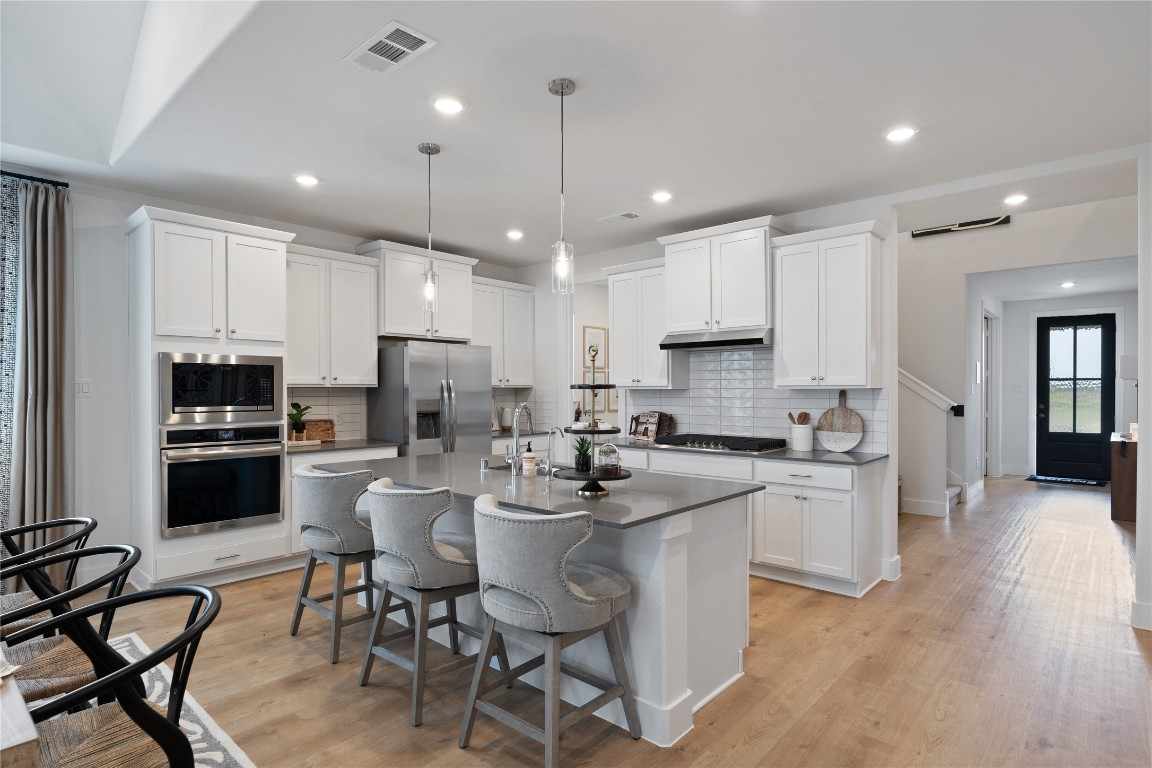 813 Green Ash Way Waller, TX 77484 - Photo 13 of 41 a kitchen with stainless steel appliances kitchen island granite countertop a stove a refrigerator a oven a sink with a dining table and chairs