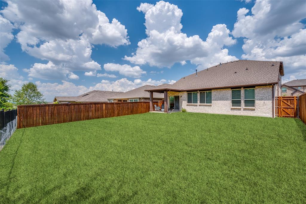 1240 Morning Ridge Trail Aubrey, TX 76227 - Photo 22 of 25 Back of property with a patio, a fenced backyard, roof with shingles, brick siding, and a gate