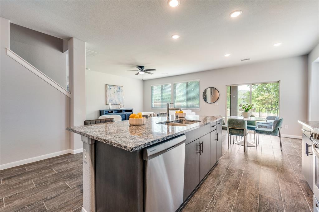 1240 Morning Ridge Trail Aubrey, TX 76227 - Photo 9 of 25 Kitchen with dishwasher, light stone countertops, a kitchen island with sink, dark wood-style floors, and recessed lighting