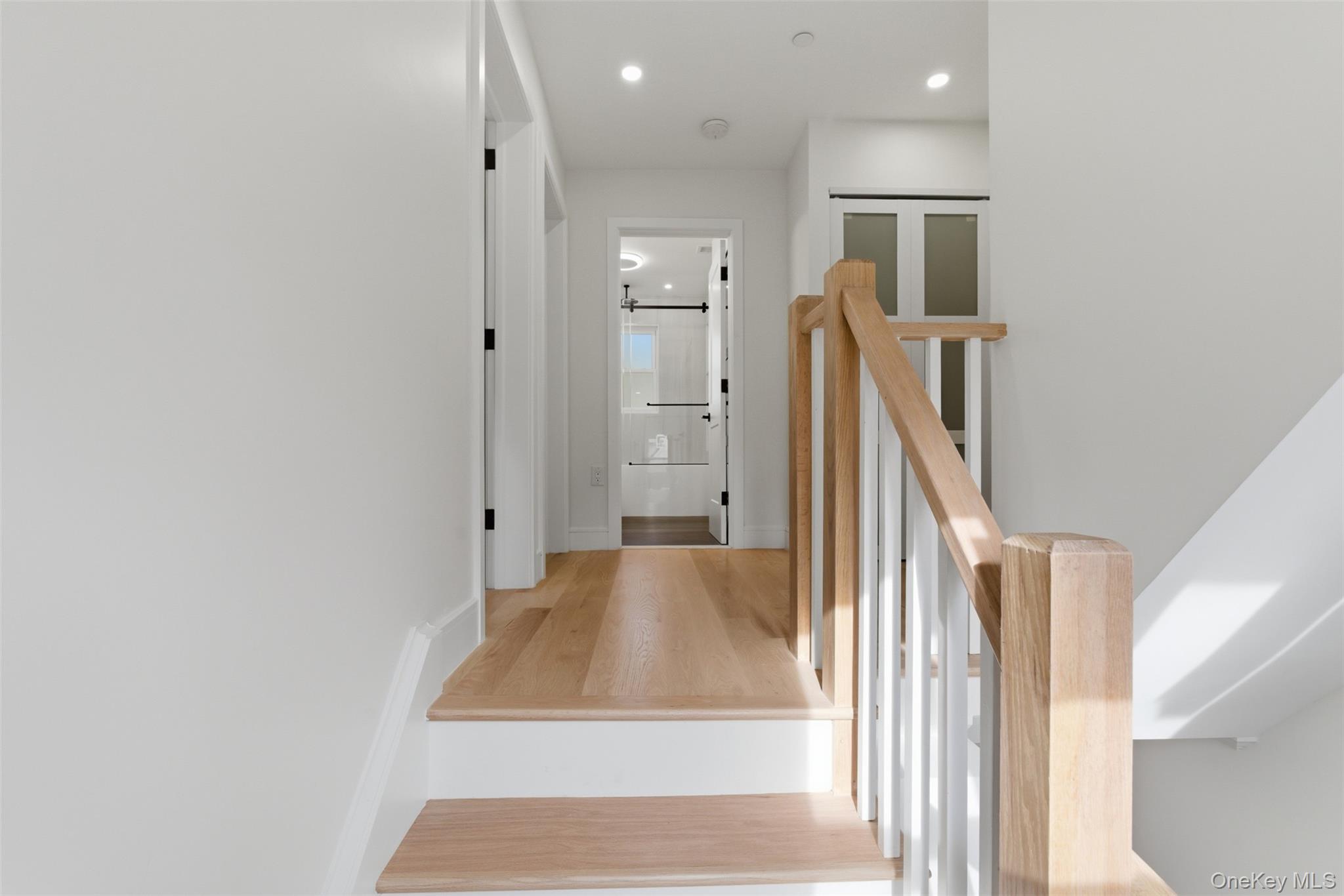 40 Calhoun Avenue New Rochelle, NY 10801 - Photo 26 of 49 Light wood-finish flooring with white risers and railings, white walls, recessed ceiling lights, and dark door hardware