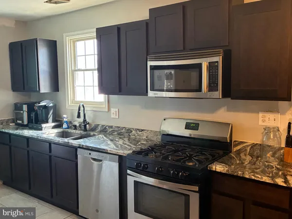 a kitchen with granite countertop stainless steel appliances a sink stove and microwave