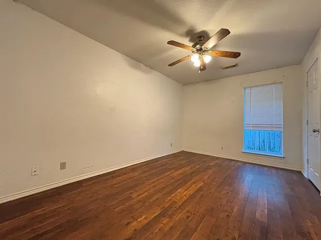 a view of an empty room with window and wooden floor