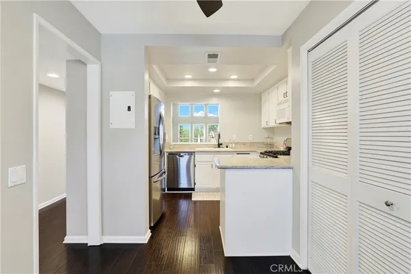 a kitchen with stainless steel appliances granite countertop a refrigerator a sink dishwasher and a stove with wooden floor