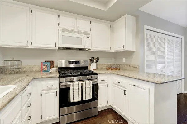 a kitchen with granite countertop white cabinets and white appliances