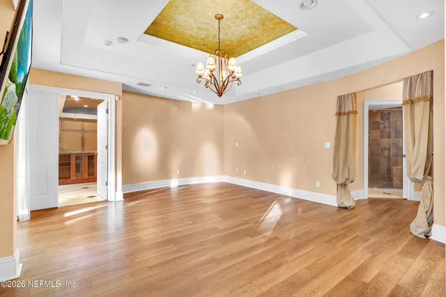 a spacious bedroom with a bed a chandelier and a large window