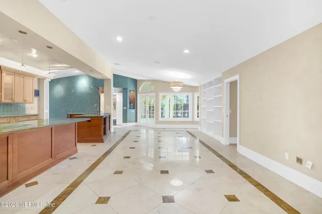 a large kitchen with kitchen island a large counter top stainless steel appliances and cabinets