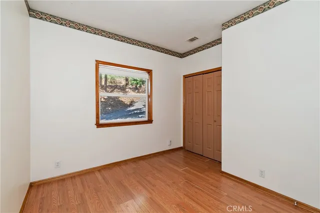 a view of an empty room with closet and wooden floor