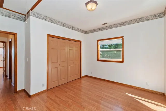 a view of an empty room with wooden floor and closet