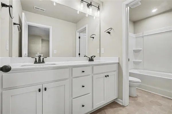 a bathroom with a double vanity sink a toilet and a bathtub