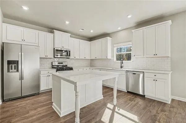 a kitchen with kitchen island granite countertop white cabinets and refrigerator