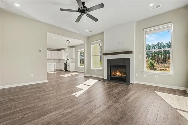 a view of a room wooden floor a ceiling fan and fire place