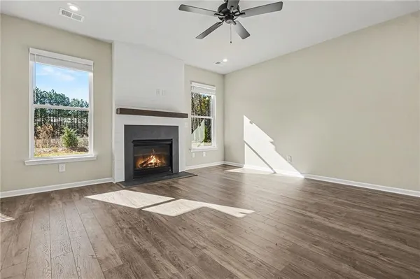a view of an empty room with wooden floor fireplace and a window