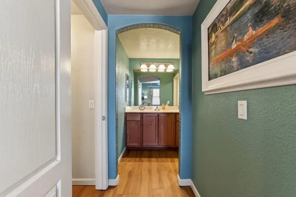a view of a hallway with wooden floor and a bathroom