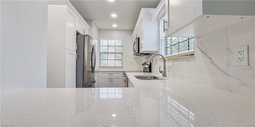 5367 Treetops Drive, Unit M101 Naples, FL 34113 - Photo 1 of 6 a kitchen with granite countertop a sink and a stove top oven