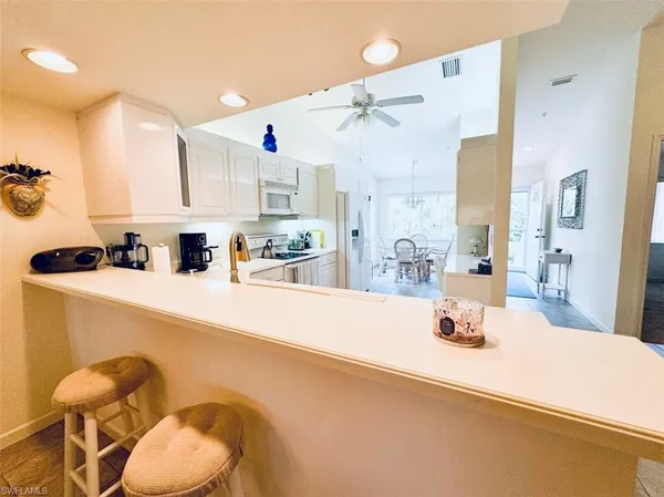 a kitchen with a sink a stove and chairs with wooden floor