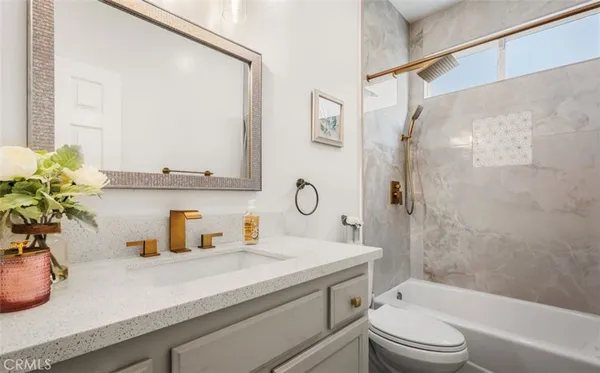 a bathroom with a granite countertop sink a toilet and shower