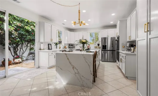 a room with stainless steel appliances kitchen island granite countertop a refrigerator and a sink