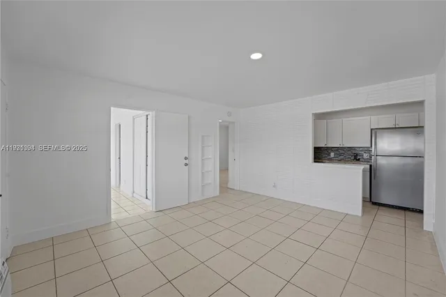 a view of a refrigerator in kitchen and white cabinets