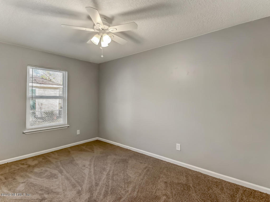 2165 Tuskegee Road Jacksonville, FL 32209 - Photo 24 of 32 an empty room with a chandelier fan and windows