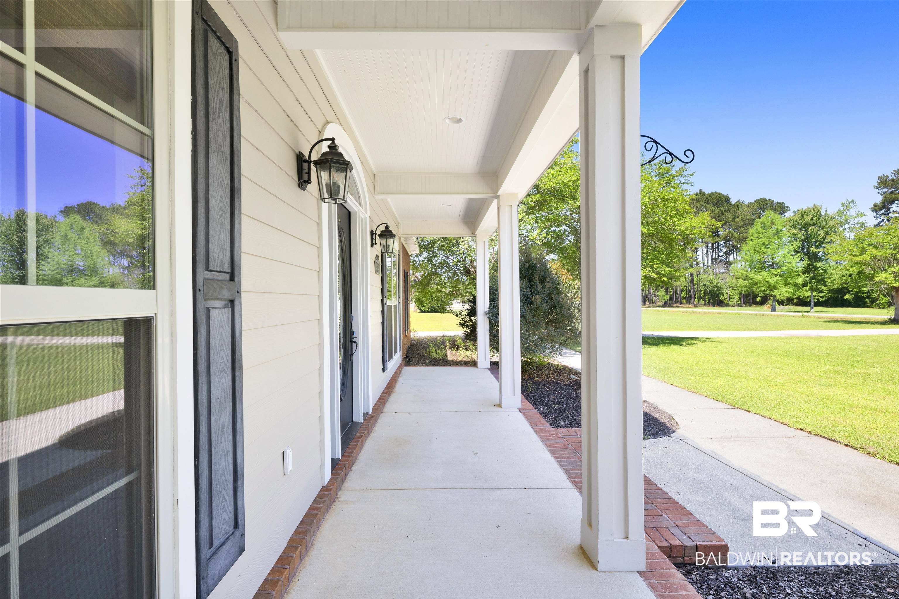 12944 Anna's Way Stapleton, AL 36578 - Photo 17 of 64 Covered front porch featuring white columns, brick accents, exterior sconce lighting, and dark window shutters