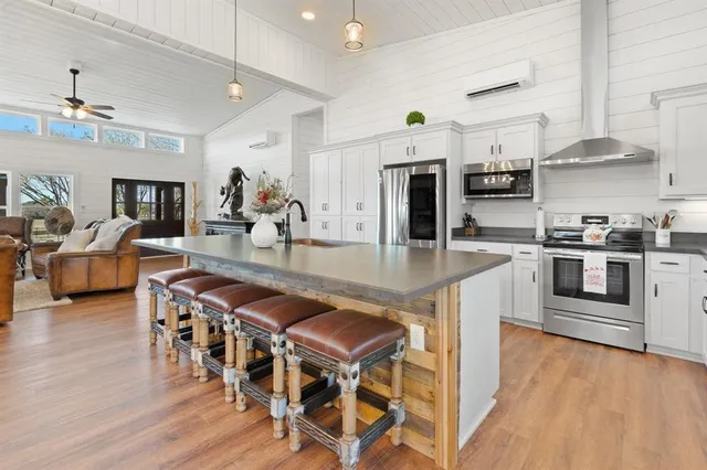 a kitchen with stainless steel appliances granite countertop a stove top oven a sink a dining table and chairs with wooden floor