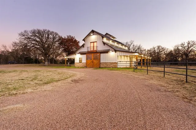a view of house with a big yard and large trees