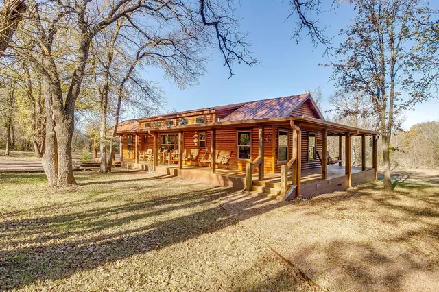 a view of a house with a large tree and wooden fence