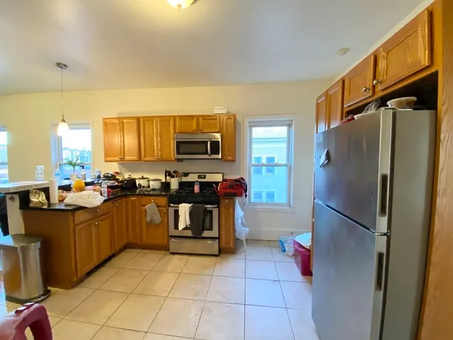 a kitchen with granite countertop a refrigerator and a stove top oven