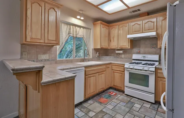 a kitchen with granite countertop a sink stove and cabinets