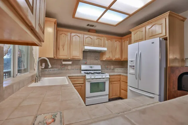 a kitchen with stainless steel appliances granite countertop a stove a refrigerator and a sink
