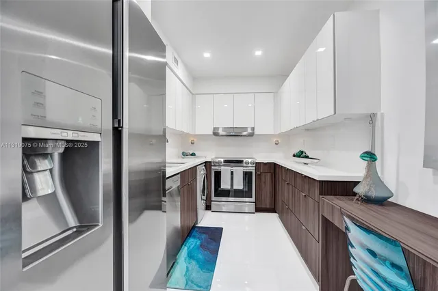 a kitchen with stainless steel appliances granite countertop a sink a refrigerator a stove and a refrigerator with white cabinets