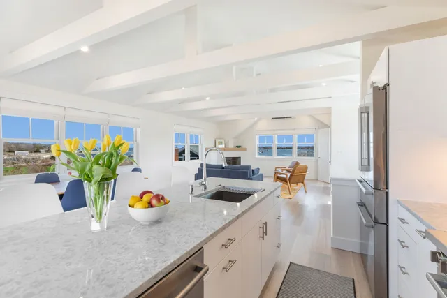 a kitchen with stainless steel appliances a refrigerator a stove a sink a dining table and chairs with wooden floor